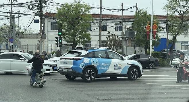지난 17일 베이징의 한 도로에서 중국 자율주행 기술기업 포니에이아이(AI)의 무인택시가 전동차와 차량이 엉킨 횡단보도를 지나고 있다. 중국은 횡단보도에서 보행자가 없을 때 녹색 신호에 차량이 지날 수 있다. 베이징/이정연 특파원