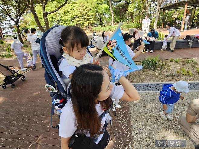 워킹맘 김나율 씨(35)가 막내 안서우 양(2)을 업고 남산 공원에서 발견한 작은 돌을 쥐어주고 있다. /사진=박수빈 기자