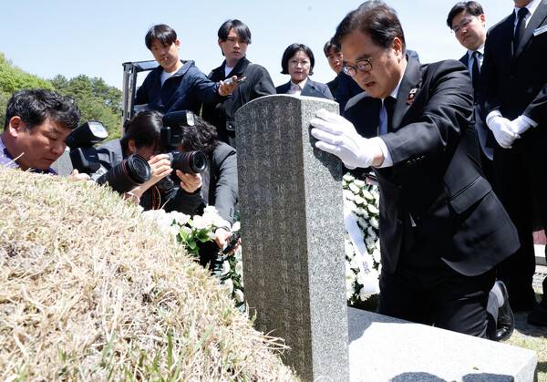 우원식 국회의장이 21일 광주 5·18민주묘지에서 오월영령에 참배 후 윤상원 열사의 묘비를 정성스럽게 닦고 있다. 판영석 기자