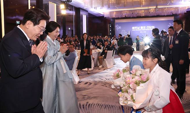 베트남을 국빈 방문중인 이재명 대통령과 김혜경 여사가 22일 하노이의 한 호텔에서 열린 동포 오찬 간담회에서 화동에게 꽃다발을 전달받고 있다.