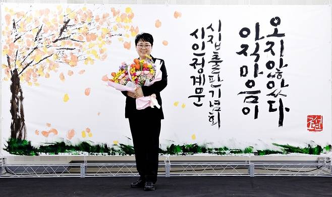 ▲ 정계문 시인이 17일 의성읍 온누리터 2층 대회의실에서 열린 두 번째 시집 '아직 마음이 오지 않았다' 출판기념회에서 꽃다발을 들고 기념촬영을 하고 있다. 정계문 시인 제공