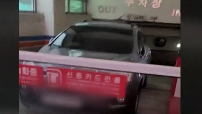 상가 건물 주차장 출입구 차단기 앞에 차량이 방치된 모습.