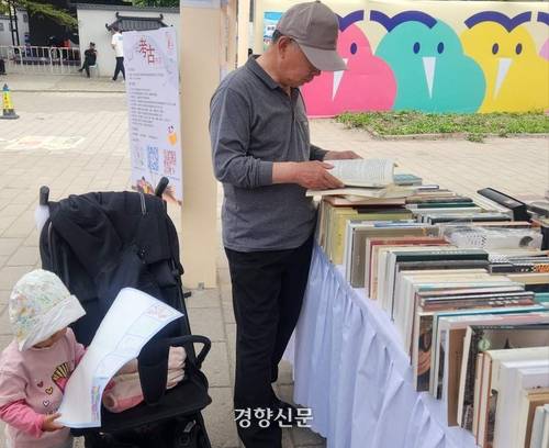 22일 원명원에서 열린 2026 베이징도서전에서 푸모씨가 인문 전문 출판사에서 역사책을 보는 동안 손녀가 도서전 지도를 따라 펼치고 있다.