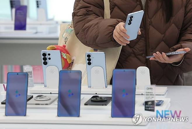 인도의 한 스마트폰 매장을 찾은 소비자가 스마트폰을 들여다보고 있다. (출처=연합뉴스)