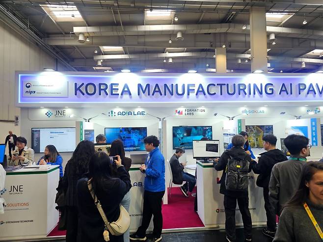 '2026 하노버 산업박람회' 16홀에 마련된 'KOREA MANUFACTURING AI PAVILION' 전경. 제이엔이웍스(JNE Works), 아디아랩(AdiaLab), 포메이션랩스(FormationLabs), 싸인랩(SignLab), 에스씨티(SCT) 등 경남·부산 권역 참가 기업 부스가 운영되는 가운데, 개막 첫날부터 다수의 글로벌 바이어가 기술 시연을 참관하고 있다.