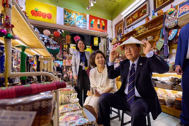 베트남을 국빈 방문 중인 이재명 대통령과 김혜경 여사가 23일(현지시간) 저녁 베트남 하노이 도심 거리 산책 도중 상점에 들어가 베트남 전통 모자인 ‘논라’를 착용해보고 있다. 이 대통령 인스타그램