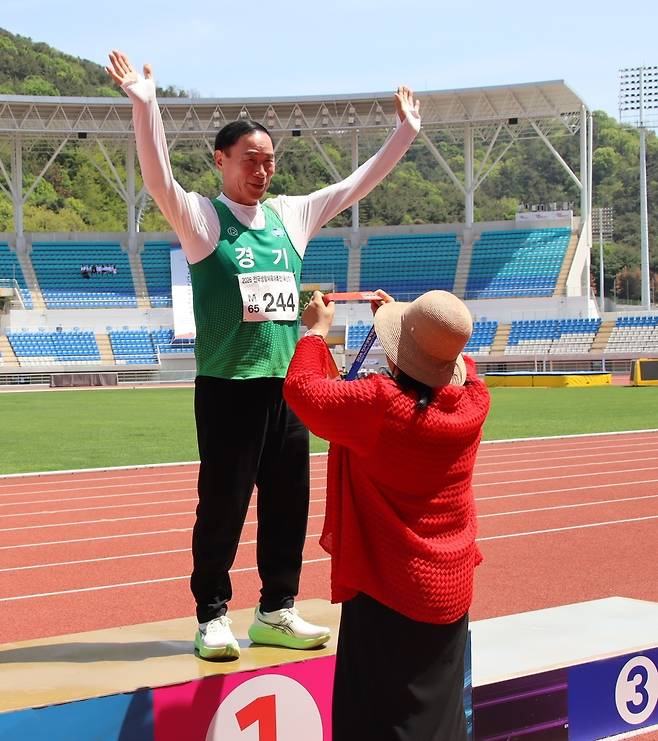 35일 경남 김해종합운동장에서 열린 2026 전국생활체육대축전 육상 남자일반부 높이뛰기(69세 이하)에서 우승을 차지한 이원성 경기도체육회장이 시상대 위에서 금메달을 받고 있다.
