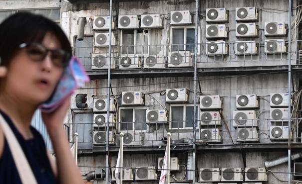 한 시민이 서울 중구 남대문 인근에 있는 건물 외벽에 줄지어 걸린 에어컨 실외기 앞을 지나가고 있다. 이상섭 기자