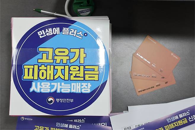 지난 24일 서울 숭인2동주민센터에 마련된 고유가 피해지원금 신청 창구에 관련 부착물과 사용 카드가 놓여 있다. ⓒ연합뉴스