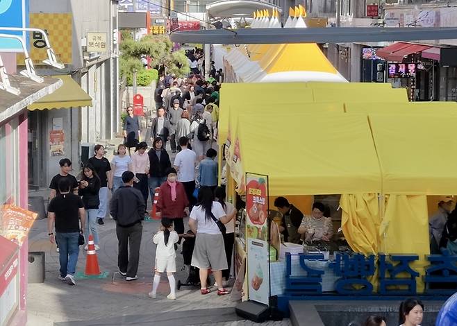 점촌점빵길 일대에 설치된 노란색 축제 부스 사이로 방문객들이 길게 이어지며 붐비고 있다. 가족 단위 시민과 관광객들이 거리 곳곳의 먹거리 부스를 찾으며 이동하는 모습에서 축제의 활기와 높은 관심을 엿볼 수 있다. <강남진기자>