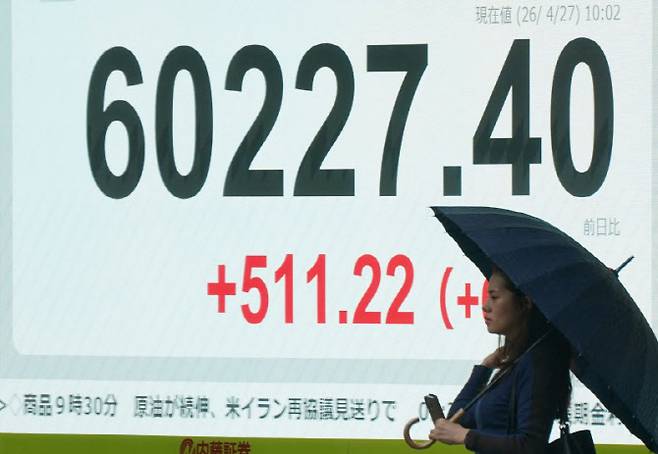 27일 일본 도쿄의 한 거리에서 한 여성이 니케이225지수가 표시된 전광판 앞을 지나가고 있다. (사진=AFP)