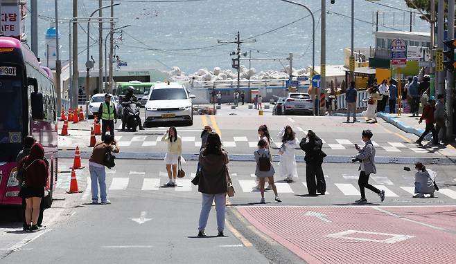 16일 오전 부산 해운대구 청사포에서 외국인 관광객들이 인생샷을 위해 도로 한복판에서 영상이나 사진을 찍고 있다. 이중 일부는 보행신호가 빨간색으로 바뀌어도 촬영을 계속했다. 이곳은 인기 만화 '슬램덩크'배경과 닮아 사진 명소로 알려져 있다./김동환 기자