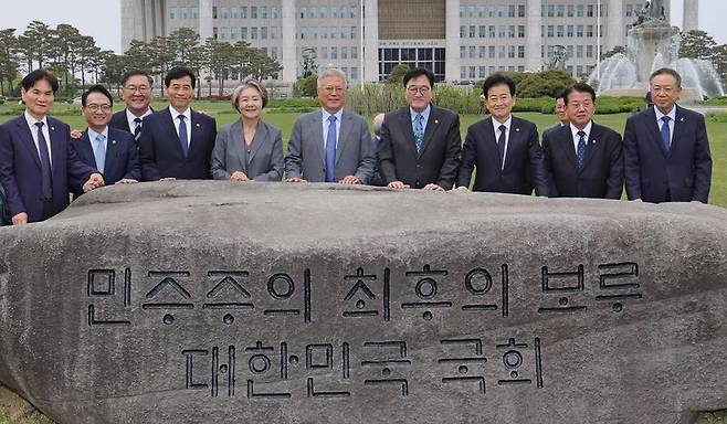 우원식 국회의장이 27일 서울 여의도 국회에서 4.27 판문점선언 8주년 기념식에 참석한 문재인 전 대통령 내외를 비롯한 참석자들에게 ‘민주주의 최후의 보루 대한민국 국회’ 문구가 새겨진 상징석 앞에서 기념촬영을 하고 있다. 뉴스1