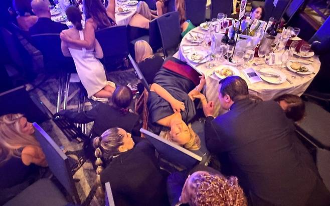 총격 공포에 아수라장 된 만찬장 - 25일(현지시간) 미국 워싱턴DC 워싱턴 힐튼 호텔에서 열린 백악관출입기자협회(WHCA) 만찬 도중 갑작스러운 총성이 울리자 놀란 참석자들이 테이블 아래로 급히 몸을 낮추고 있다. 워싱턴DC 로이터 연합뉴스