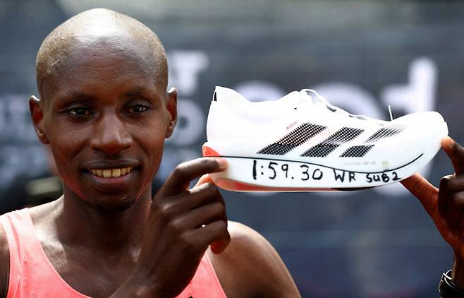 케냐의 세바스티안 사웨가 26일 영국 런던 마라톤 남자 엘리트 레이스에서 우승한 뒤 자신이 세운 서브2 기록을 적은 레이싱화를 들어 올리며 기뻐하고 있다. 아래 작은사진은 시상식에서 트로피를 들고 기념 촬영하고 있는 모습. 로이터·AFP연합뉴스