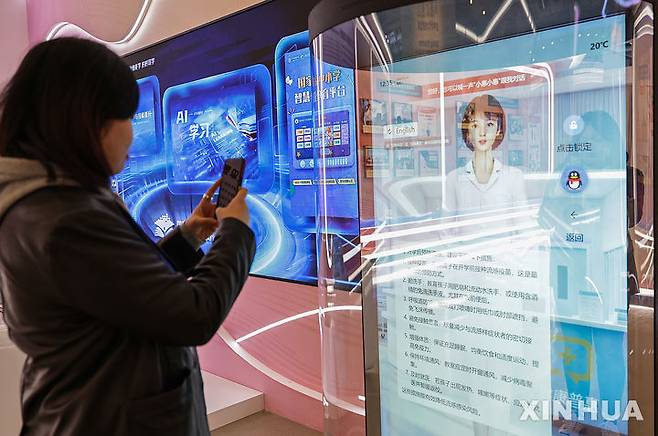 [베이징=신화/뉴시스] 중국 베이징에서 열린 인공지능(AI) 관련 전시회를 찾은 입장객이 AI 인터랙티브 화면을 스마트폰으로 찍고 있다. 자료사진. 2026.02.26