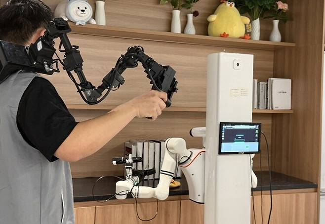 28일 베이징 스징산구 베이징인간형로봇데이터훈련센터에서 로봇이 거실로 꾸며진 환경에서 책 정리를 학습하고 있다. 베이징/이정연 특파원