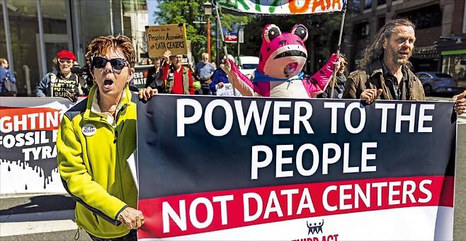 < “데이터센터에 쓸 전기, 우리에게 달라” > 지난 21일 미국 워싱턴DC에서 열린 데이터센터 콘퍼런스 행사장 앞에서 환경운동가들이 데이터센터 확장에 반대하는 시위를 벌이고 있다. 이들은 데이터센터 때문에 미국 전역의 에너지 수요가 급증한다며 ‘제2 석탄산업’이라고 불렀다.  EPA연합뉴스
