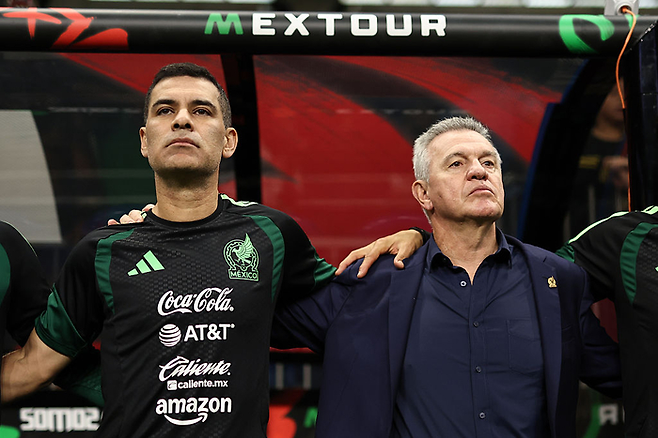 멕시코 하비에르 아기레 감독(오른쪽)이 지난해 11월 파라과이전에 앞서 라파엘 마르케스 수석코치와 함께 어깨동무를 하고 국가 제창을 하고 있다. Getty Images코리아