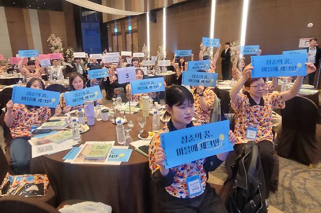 2026 청년마을 발대식에서 청년들이 ‘청춘의 꿈, 마을에 체크인’ 슬로건을 들어 올리고 있다. 김해=박태근 기자 ptk@donga.com