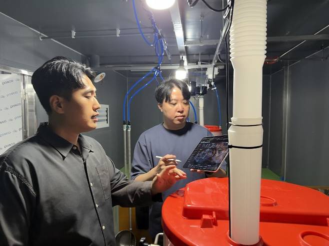 ETRI 연구진이 제주형 양돈 AX 스마트팜 현장에서 스마트 기기를 이용해 돈사 내부 환경 제어 시스템을 점검하고 있다. ETRI 제공