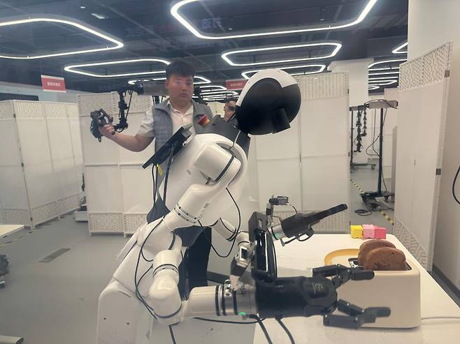 과거 중국 대표 철강 생산기지였던 중국 베이징시 스징산구 서우강원이 로봇 체험 테마파크로 바뀌었다. 로봇이 토스트를 사용하는 과정을 학습하고 있다. 베이징=이혜미 특파원