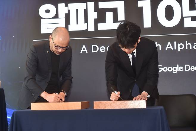 데미스 허사비스(왼쪽) 구글 딥마인드 CEO와 신진서 9단이 29일 서울 중구 웨스틴 조선호텔에서 기념 대국을 펼친 뒤 바둑판에 사인을 하고 있다. 사진 제공=한국기원