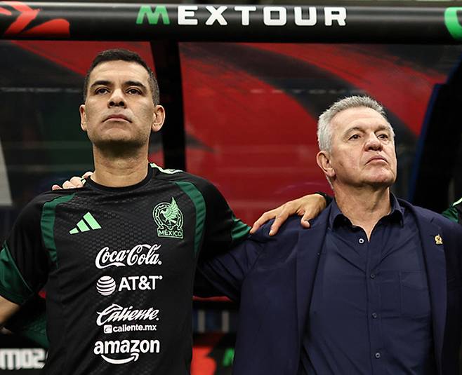 멕시코 하비에르 아기레 감독(오른쪽)이 지난해 11월 파라과이전에 앞서 라파엘 마르케스 수석코치와 함께 어깨동무를 하고 국가 제창을 하고 있다. 게티이미지코리아