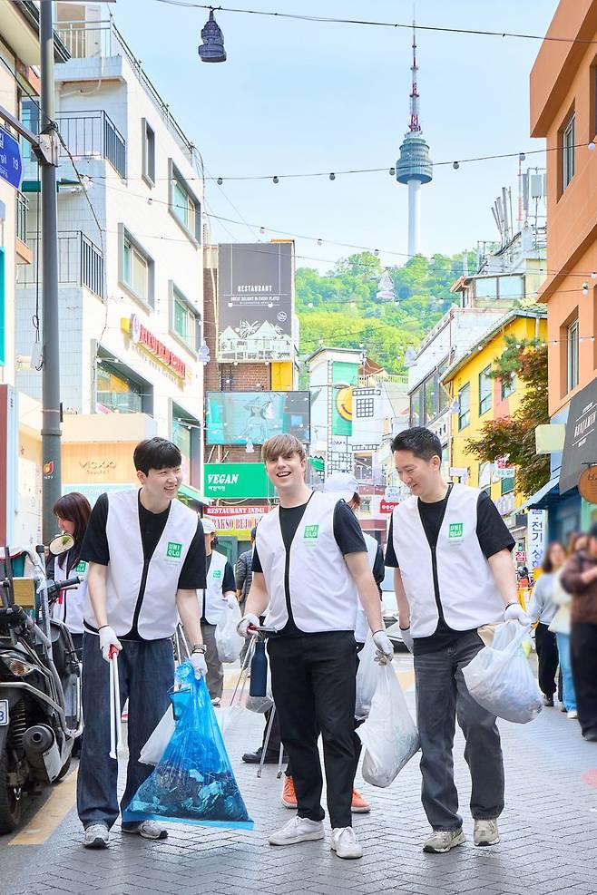 방송인 줄리안(가운데)과 최우제 에프알엘코리아 공동대표(오른쪽)가 명동 거리에서 쓰레기를 줍고 있다. 유니클로 제공