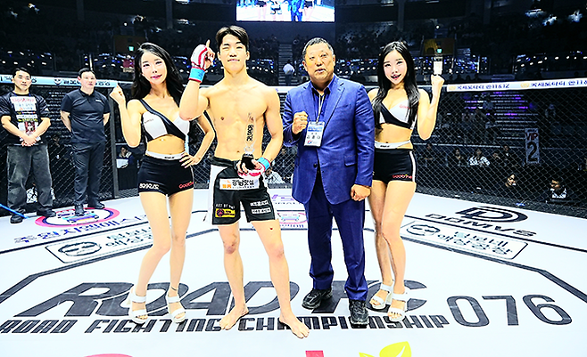 KMMA 챔피언 출신 김지경이 2026년 3월 서울특별시 중구 장충체육관 특설 케이지에서 로드FC 76 승리 기념 촬영을 하고 있다. 맨 왼쪽은 제3대 로드FC 밴텀급 챔피언을 지낸 팀AOM 이윤준 관장. 사진=세계격투스포츠협회