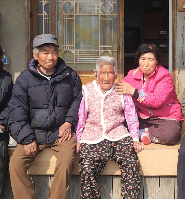 7일 '보화상 효행상'을 수상하는 안동시 도산면 의일리 김순옥씨(오른쪽)가 남편 김진만씨, 시어머니 박분돌 여사와 함께 자택 툇마루에 앉아 환하게 웃고 있다. 김씨는 치매와 노환으로 거동이 불편한 시어머니를 47년째 직접 수발해 온 공로를 인정받았다. 보화원 제공
