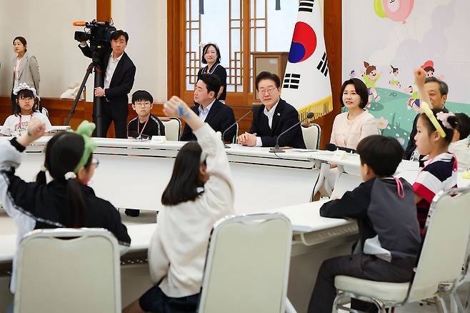 이재명 대통령과 김혜경 여사가 5일 제104회 어린이날을 맞아 전국의 어린이와 보호자 200여명을 청와대 본관으로 초청했다. 이날 참석한 어린이들이 충무실에서 발언 기회를 얻기 위해 손을 들고 있다.