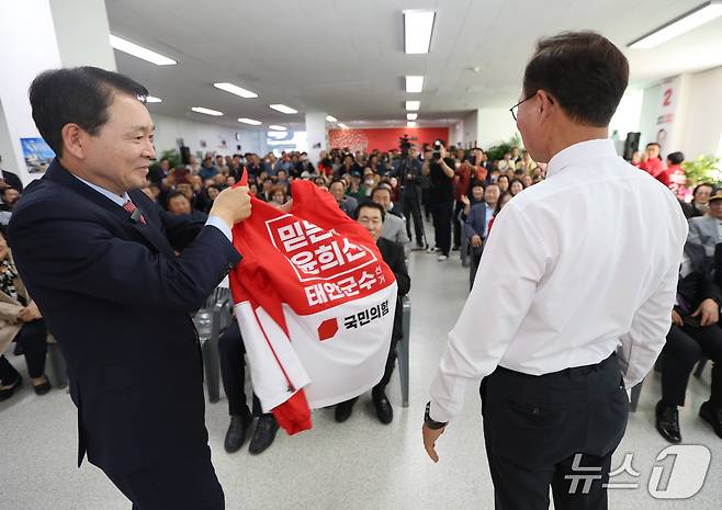 성일종 의원(왼쪽)이 윤 후보에게 선거 운동복을 입혀주며 필승을 기원하고 있다.(윤 후보 캠프)제공. 재판매 및 DB금지)2026.5.6/뉴스1