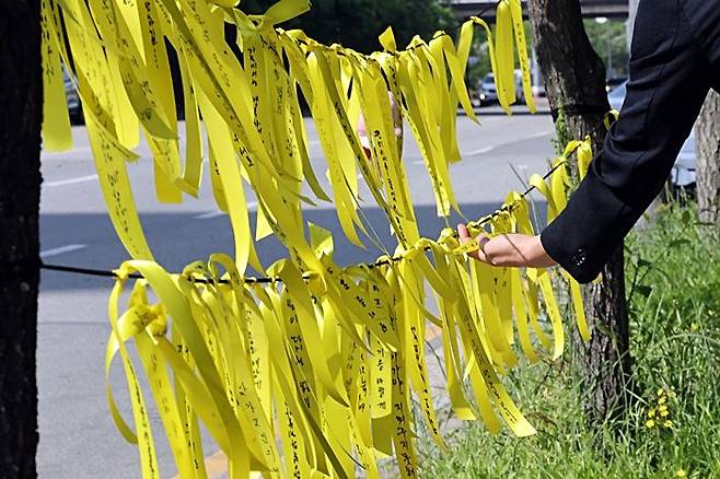 7일 고교생 흉기 살인사건이 발생한 광주 광산구 월계동 현장에 마련된 추모공간에서 한 시민이 노란리본에 적힌 메시지를 살펴보고 있다. ⓒ연합뉴스