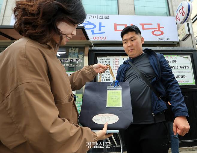 발달장애청년허브 ‘사부작’ 청년 ‘냐옹’(오른쪽)이 지난달 21일 서울 마포구 성산동에서 마을주민 ‘랄라뿅’에게 주문한 책을 배달하고 있다. 서성일 선임기자