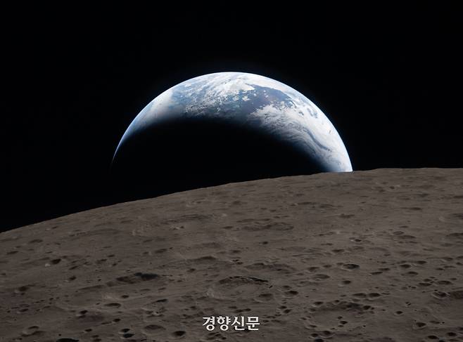 아르테미스 2호가 달 근접 비행 중 창을 통해 포착한 지구의 일몰 모습. 푸른빛의 지구가 분화구로 뒤덮인 달 표면 뒤로 지고 있다. NASA 제공