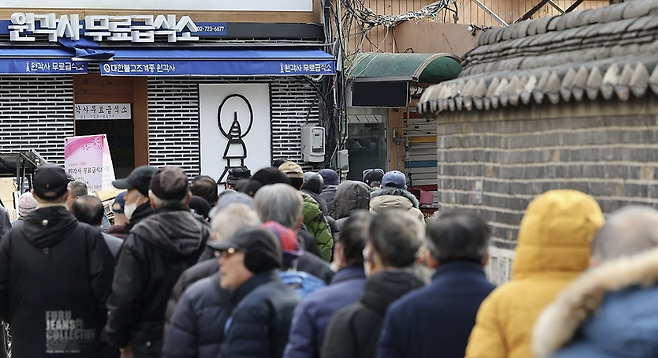 지난해 12월 24일 서울 종로구 탑골공원 앞에서 어르신들이 무료 급식을 받기 위해 줄을 서 있다. 연합뉴스