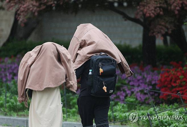 서울 종로구 경복궁 인근에서 외국인 관광객들이 겉옷으로 비를 비하고 있다. [연합뉴스 자료사진]