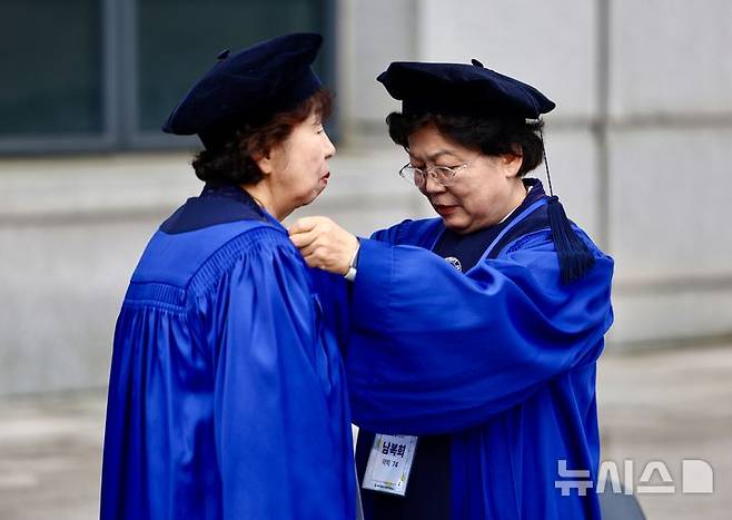 [서울=뉴시스] 김명년 기자 = 12일 오전 서울 용산구 숙명여자대학교 백주년기념관에서 열린 '졸업 50주년 홈커밍데이' 행사에서 학위복을 입은 50여년 전 졸업생이 동문의 옷매무새를 살펴주고 있다. 2026.05.12. kmn@newsis.com
