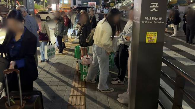 지난 7일 새벽 지하철 막차가 끊기자 서울역 택시 승강장 인근에서 외국인 관광객들이 택시를 잡기 위해 핸드폰 화면을 바라보며 기다리고 있다. 박호수 기자