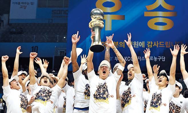 부산 KCC가 13일 프로농구 챔피언결정 5차전에서 고양 소노를 꺾고 시리즈 전적 4승 1패로 우승했다. 주장 최준용이 우승 트로피를 힘차게 들어 올리자 선수단이 환호하고 있다. KCC는 정규리그 6위로 첫 챔프전 우승을 차지한 팀이 됐다. /연합뉴스