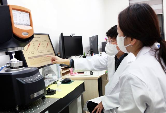 코스맥스 CAI연구소 관계자(앞쪽)와 박준동 숙명여대 화공생명공학부 교수가 AI로 분석한 제형에 대해 상의하고 있다. [코스맥스 제공]
