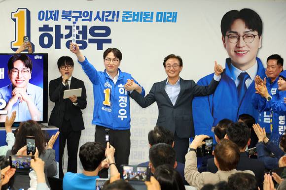 부산 북갑 국회의원 보궐선거에 출마하는 더불어민주당 하정우 후보가 10일 오후 부산 북구에서 열린 선거사무소 개소식에서 전재수 부산시장 후보가 건넨 '북구의 미래'가 적힌 바톤을 넘겨 받은 뒤 손을 잡고 있다. 북갑은 전재수 후보가 3선을 지낸 곳이다. 2026.5.10 [사진=연합뉴스]