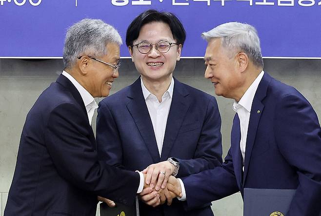 14일 원전수출 전략적 파트너십 협약식에서 김동철 한국전력공사 사장(왼쪽)과 김회천 한국수력원자력 사장이 손을 맞잡으며 웃고 있다. 가운데는 김정관 산업통상부 장관. [뉴스1]