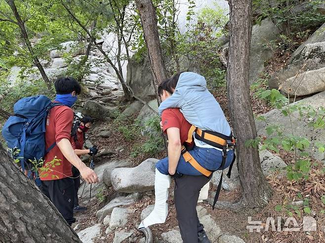 [서울=뉴시스]4일 오후 구조 출동 지령을 받은 북한산 산악구조대 대원들이 족두리봉 하단에서 실족한 여성을 업고 하산하고 있다. (사진=북한산 산악구조대 제공) 2026.05.04. photo@newsis.com