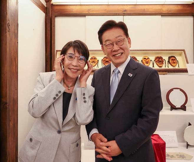 안경을 쓰고 웃고 있는 이재명 대통령과 다카이치 사나에 일본 총리(좌측) [일본 내각 공보실 공식 계정 엑스 게시물 캡처. 재판매 및 DB 금지]