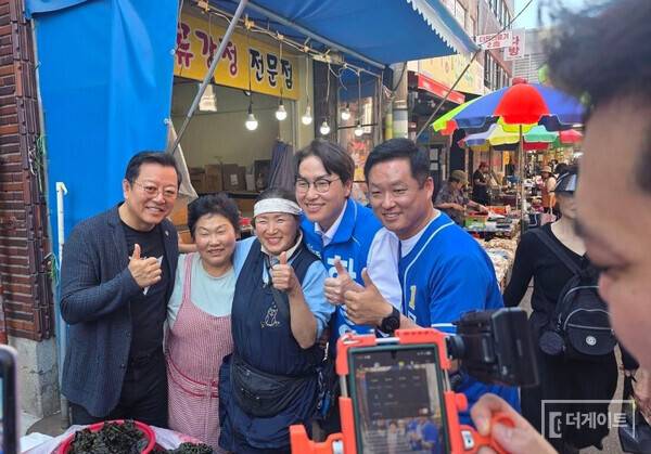 이기영 배우(사진 왼쪽부터)와 구포시장 상인, 하정우 부산 북구 갑 국회의원 보궐선거 후보자, 문영남 북구 제1선거구(북구 구포제1동, 구포제2동, 구포제3동, 덕천제1동, 덕천제2동, 덕천제3동, 만덕제2동, 만덕제3동) 후보자가 함께 기념사진을 찍는 장면(사진=더게이트)