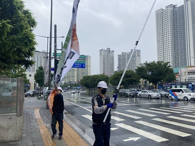 비가 내린 20일 서울시 기동정비반 직원들이 용산구 삼각지역 횡단보도에 설치된 불법 현수막을 철거하고 있다. 손인규 기자