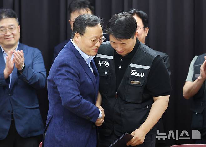 [수원=뉴시스] 김종택기자 = 20일 경기도 수원시 장안구 경기고용노동청에서 열린 삼성전자 임금협상을 마친 후 여명구 삼성전자 DS(디바이스솔루션·반도체 사업 담당) 피플팀장과 최승호 삼성그룹 초기업노동조합 삼성전자지부 위원장이 잠정 합의한에 서명한 후 손을 맞잡고 있다. (공동취재) 2026.05.20. photo@newsis.com