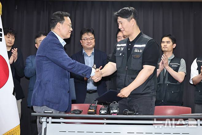 [수원=뉴시스] 김종택기자 = 20일 경기도 수원시 장안구 경기고용노동청에서 열린 삼성전자 임금협상을 마친 후 여명구 삼성전자 DS(디바이스솔루션·반도체 사업 담당) 피플팀장과 최승호 삼성그룹 초기업노동조합 삼성전자지부 위원장이 잠정 합의한에 서명한 후 손을 맞잡고 있다. 2026.05.20. photo@newsis.com
